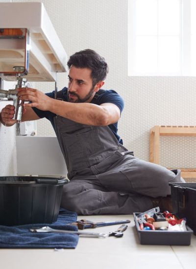 male-plumber-working-to-fix-leaking-sink-in-home-